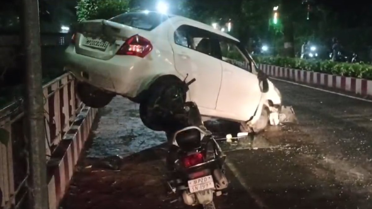 तेज रफ्तार का कहर: कार और स्कूटी में जोरदार भिड़ंत, टक्कर के बाद डिवाइडर पर लटकी Car, एक की हालत गंभीर